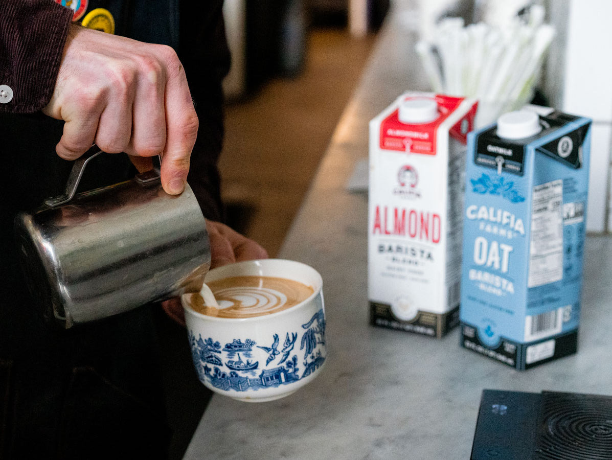 almond milk and oat milk sitting next to coffee