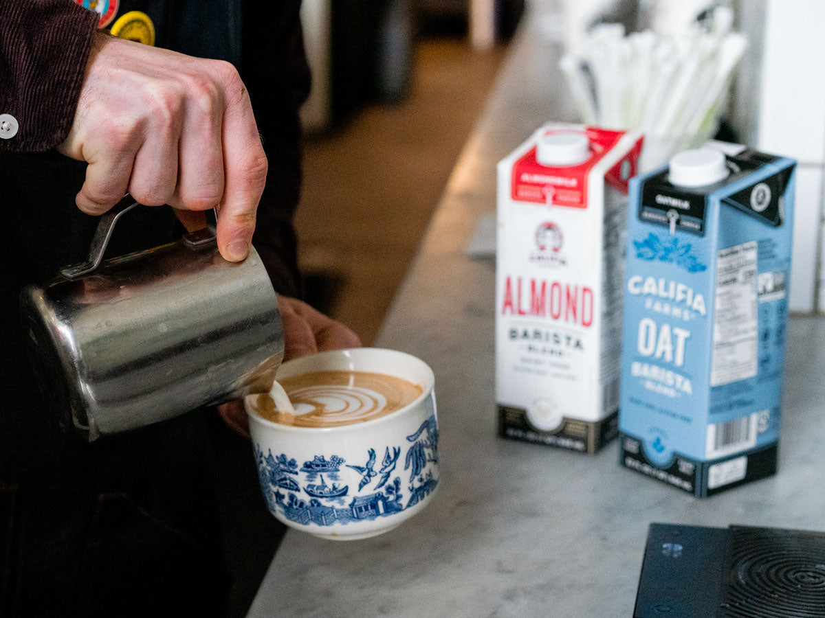 almond milk and oat milk sitting next to coffee