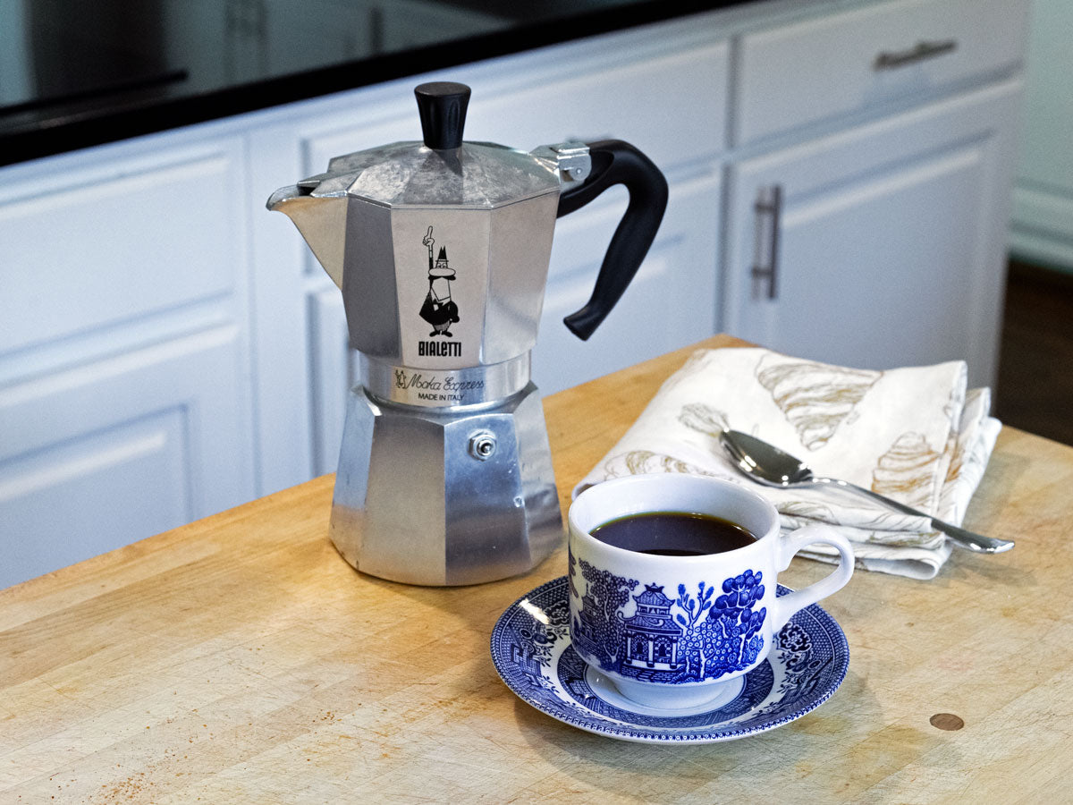 Bialetti Moka Pot sitting on counter with cup of coffee