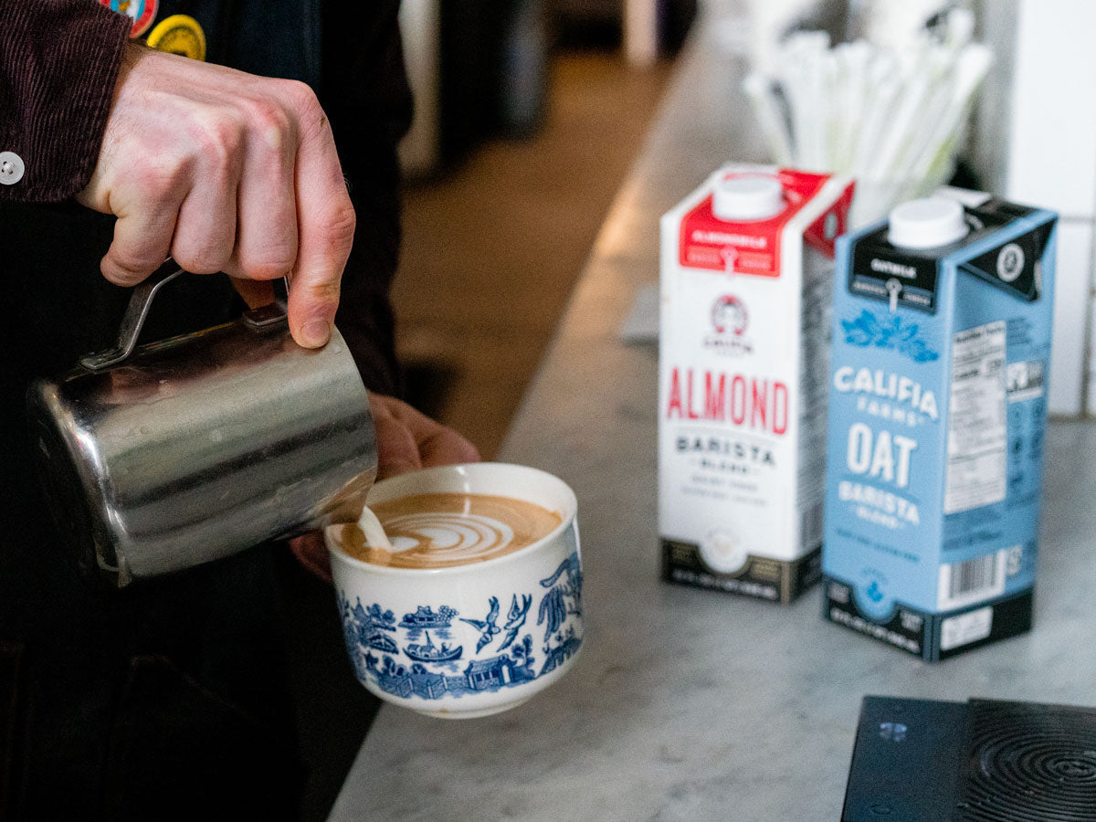 almond milk and oat milk sitting next to coffee