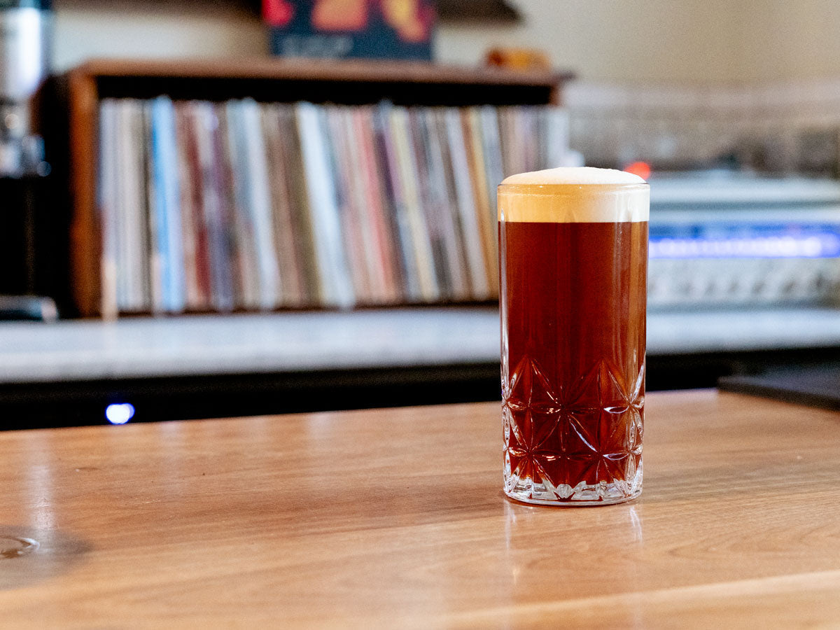 glass of cold brew with foam on a wooden table