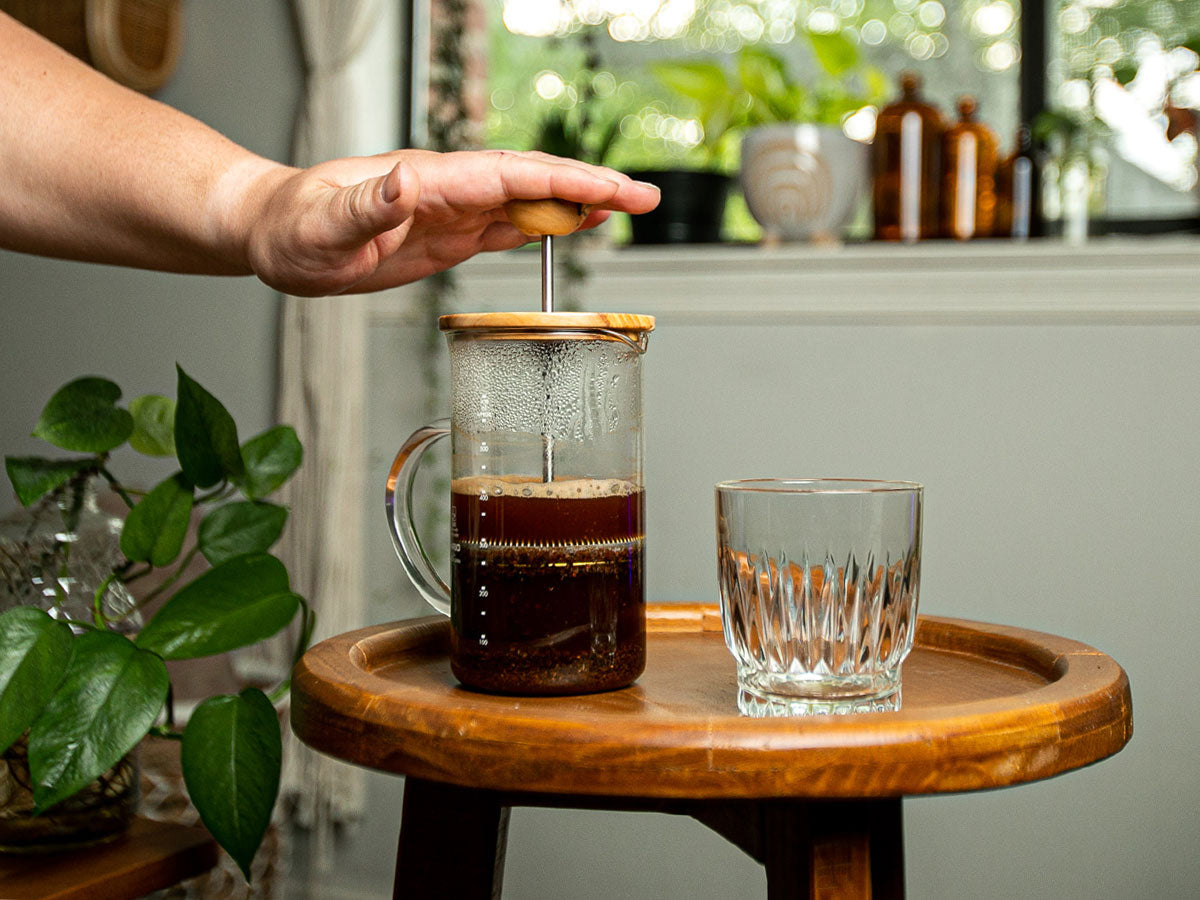 person using a French press coffee maker to make coffee